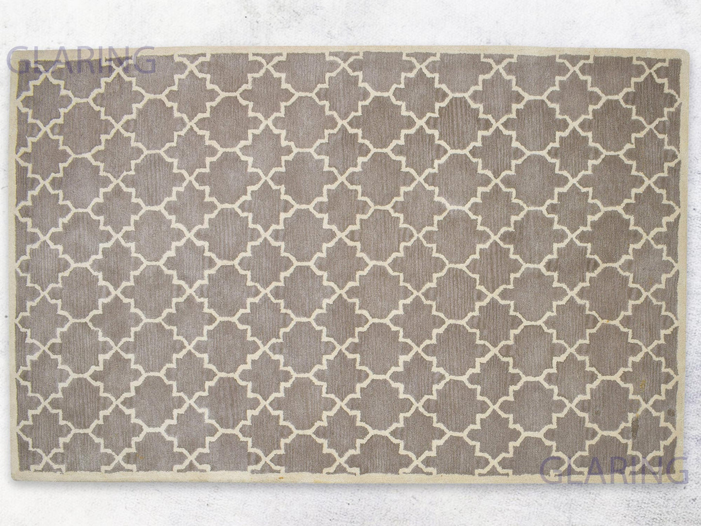A rectangular, handmade rug with a geometric design in brown and ivory colors, indicating a handmade Moroccan style.