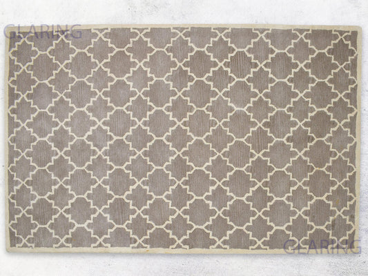 A rectangular, handmade rug with a geometric design in brown and ivory colors, indicating a handmade Moroccan style.