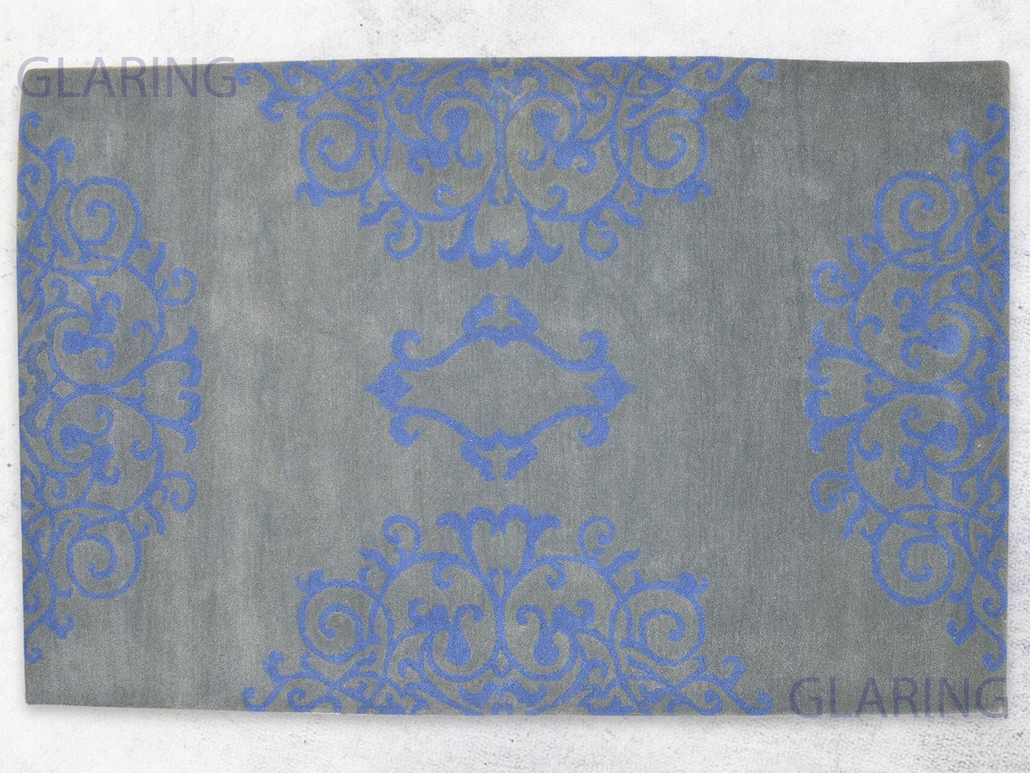 A rectangular rug with a floral design in grey and blue, with a soft medium-cut pile height.