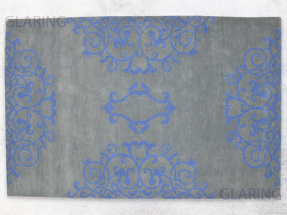 A rectangular rug with a floral design in grey and blue, with a soft medium-cut pile height.