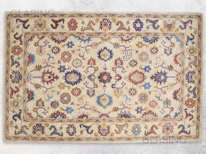 A rectangular, handmade Bohemian rug with an Oriental design featuring geometric and floral patterns in beige, blue, and red colors.